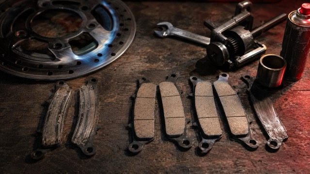 Plaquettes de frein motocross usées et neuves sur établi atelier, comparatif Brembo CL Brakes Prox