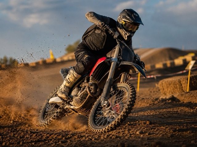 Rider motocross en phase de freinage progressif sur piste, rodage plaquettes neuves
